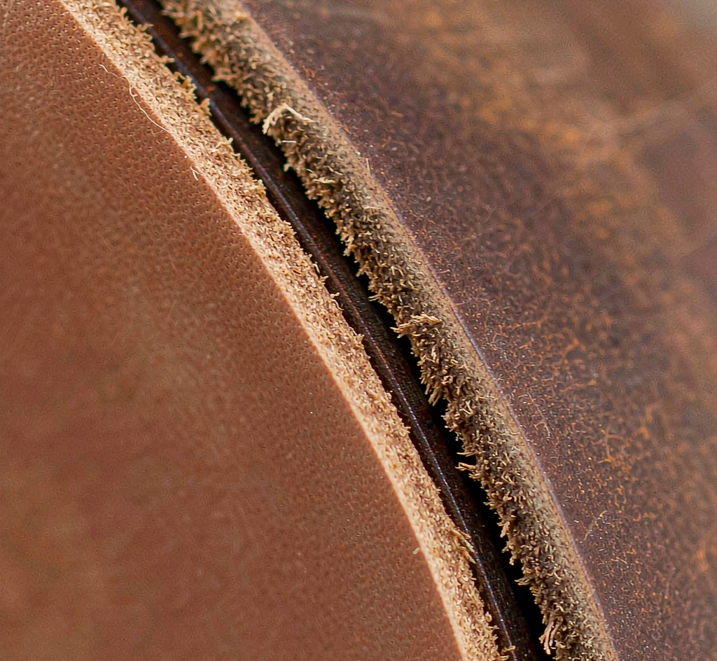 Macro close-up of chrome-tanned and vegetable-tanned leather belt edges showing fiber density and surface grain texture differences